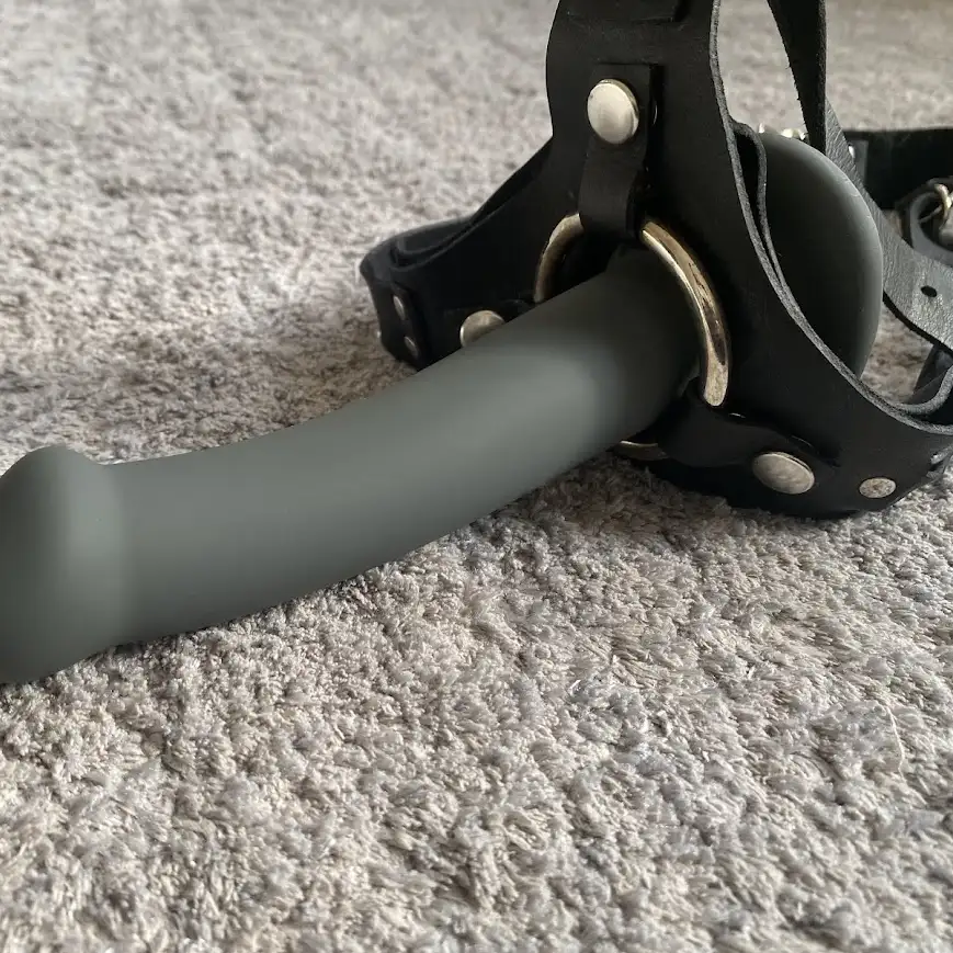 Testade strap-on-selen Miss Bond Leather Harnesk med dildo i på en grå matta