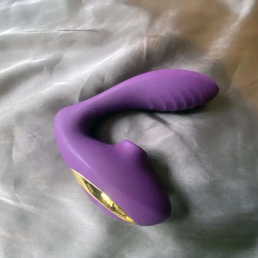 Testad vibrator Tracys Dog Klitoris sucker i lila på ett beige silkeslakan