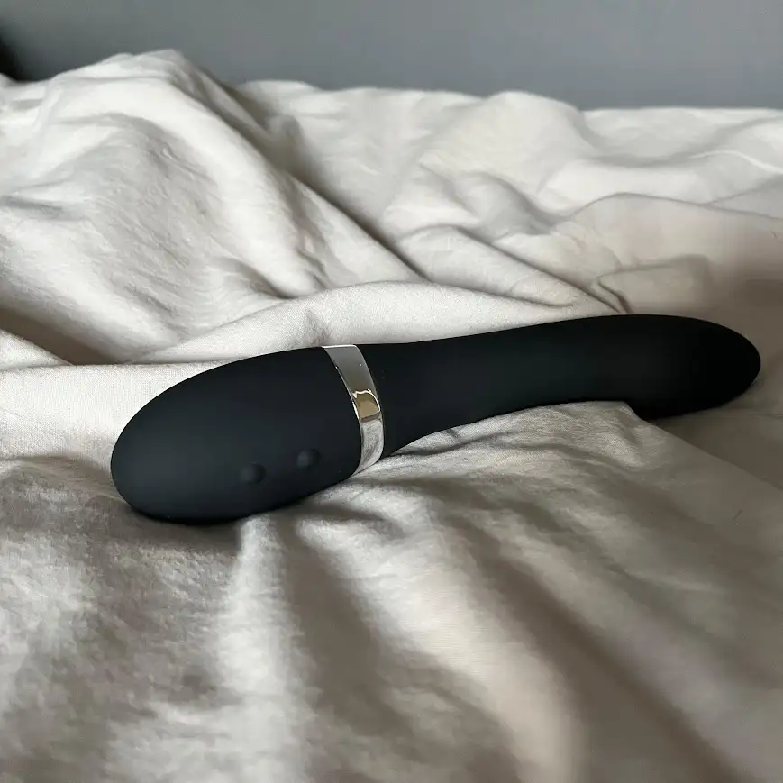 Recensionsexemplar av Sinful Slim Curve G-spot Vibrator med synliga knappar på ett vitt täcke